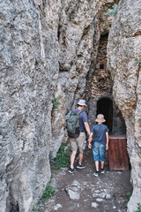 A boy and his grandfather walking into in a through grotto located in the rock