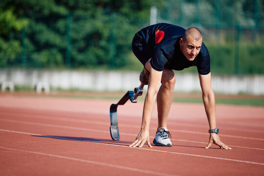 Disabled runner with artificial leg in start position on running track at the stadium.