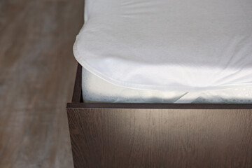 Fototapeta na wymiar Wooden bed with a high mattress and a covered white mattress cover
