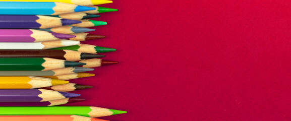 Ready to draw concept, banner background with color pencils on a red desktop, copy space, top view photo
