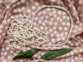 Beige background fabric textile dotted with white pearls and green leaves 