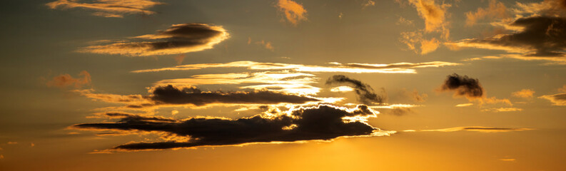 The sun shines through the clouds at sunset