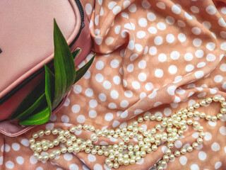 shower gel on a beige background to a point with accessories a handbag and pearls and green leaves of a green plant