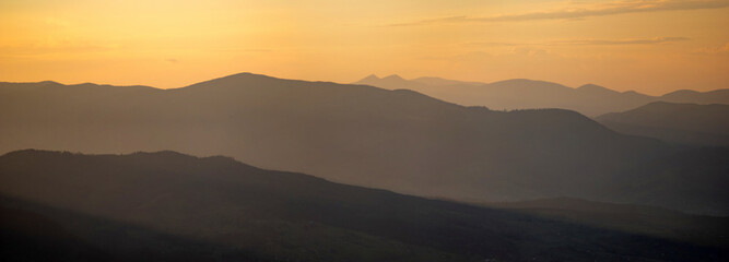 Silhouettes of the Carpathian mountains in the haze at sunset