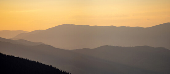 Silhouettes of the Carpathian mountains in the haze at sunset