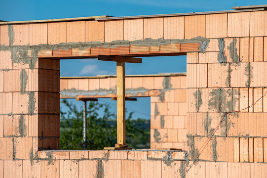 Bau eines Hauses mit Holzst&uuml;tzen in einem neu gemauerten Fenster