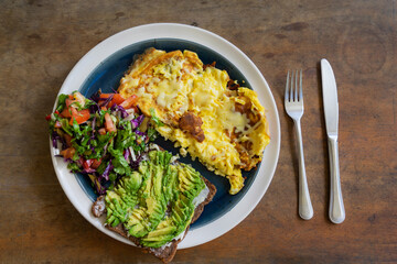 Rural breakfast with omlet, salad and toast with avocado on the wooden table