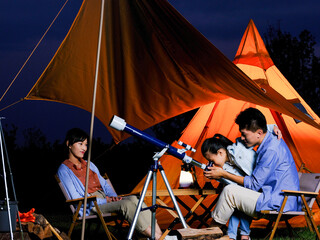 A happy family of three using telescopes outdoors