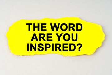 On a white background lies yellow paper with the inscription - THE WORD ARE YOU INSPIRED