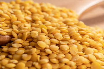 Raw yellow lentils in a wooden spoon