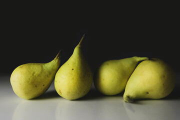Close-up of four pears, dark background