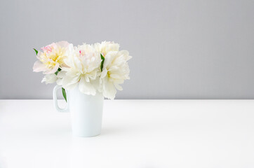 Bouquet of beautiful peonies in a white vase on a white background