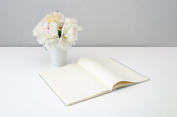 Blank notepad on a background of flowers of peonies on a white background