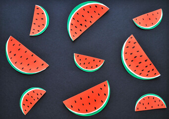 Pieces of watermelon made from paper on dark background