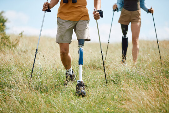 Unrecognizable disabled hikers with leg prostheses walking through nature.