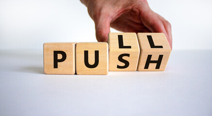 Pull or push symbol. Businessman turns wooden cubes and changes the word 'push' to 'pull'. Beautiful white background, copy space. Business and pull or push concept. - obrazy, fototapety, plakaty