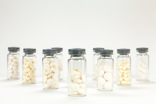 Set of pills on cristal jar for vaccines on coloured background