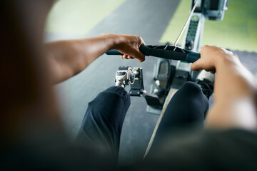 Close-up of sportsman with disabled leg exercises on rowing machine in gym.