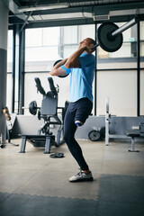 Young amputee exercises strength with barbell during sports training in a gym.