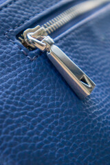 Natural or artificial leather texture. Fragment of a blue bag with a zipper and stitching. Zipper...