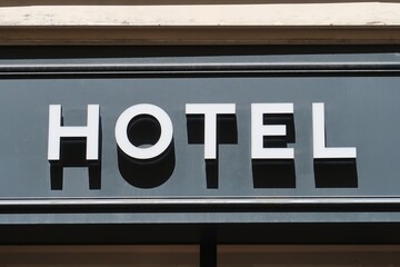 Hôtel, enseigne en lettres capitales blanches sur fond gris, sur la façade d'un établissement à...