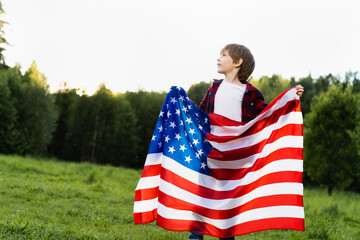 little boy with the American flag in nature, the concept of patriotism and the holiday of independence USA