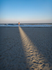 Man walks through sunlight on the beach