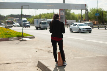 The girl is waiting for the car. Waiting for the bus on the highway.