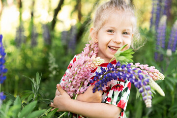 Happy little girl summer in lupin colors, portrait of a blond girl in nature