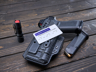 Concealed Carry Permit laying on handgun in holster with spare magazine and hand light - obrazy, fototapety, plakaty