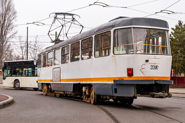 Old electric tram driving through the streets of downtown Bucharest on cloudy day