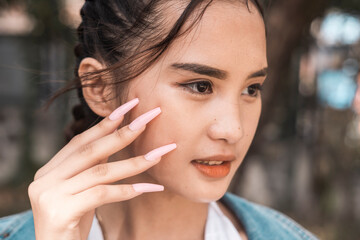 A young teenage woman candidly posing and showing off her long fashionable square fake nails.