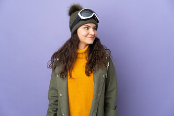 Teenager Russian girl with snowboarding glasses isolated on purple background looking side