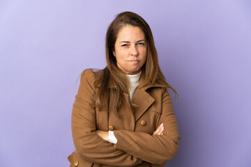 Middle age Brazilian woman isolated on purple background with unhappy expression