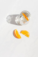 Fototapeta na wymiar Still life orange slices and iridescent glass on white marble background