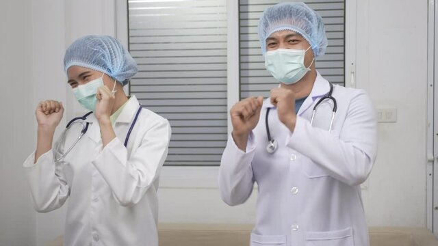 Team of medical workers doctor man and woman dancing happy and cheerful in hospital after complete success COVID-19 Medicine And Health Care Concept