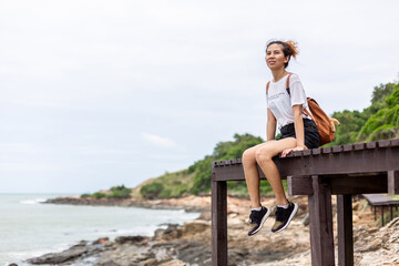 Woman sitting and looking at nature See the beautiful beach and sea on the wooden bridge.