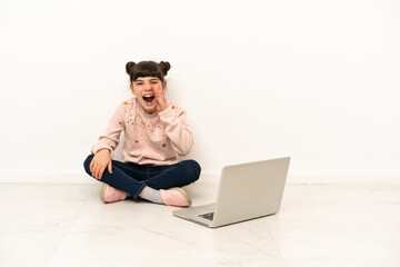 Little girl with a laptop sitting on the floor shouting with mouth wide open