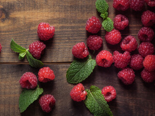 Raspberry and peppermint berries on a wooden table, top view.