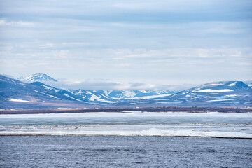 Landscape with ice break in Chukotka sea against the snowy hills