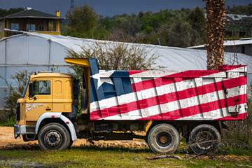 Dump truck with the image of the national flag of Liberia is parked against the background of the...