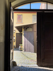 half opened gate in an old building with a view into the yard with a wooden barrel