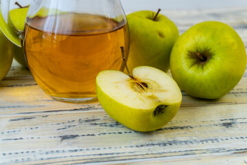 Green apples and jug with apple juice on wooden background