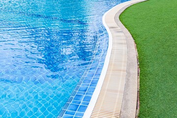 Fototapeta na wymiar Wide swimming pool and green artificial turf inside the villa