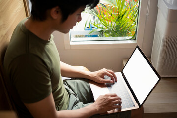 Asian man using laptop at home.