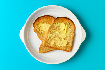 Breakfast toast bread with butter on white plate blue background