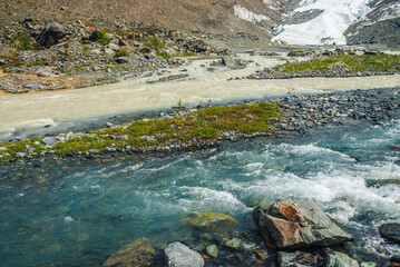 Sunny alpine landscape with confluence of two various mountain rivers. Beautiful clear creek flows...