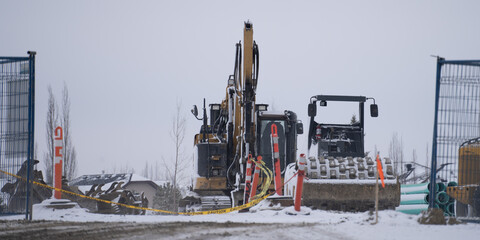 Construction equipment behind a wire mesh fence on site
