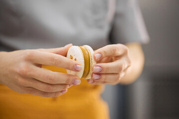 A bright girl holds fresh cakes and macaroons in her hands