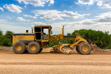 Grader Road Construction Grader industrial machine on construction of new roads. the blade of a motor grader in the process of leveling a sandy road foundation. Grader is working on road construction. - obrazy, fototapety, plakaty